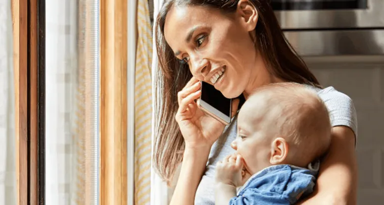 Caregiver on mobile phone while holding baby